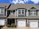 Charming townhome featuring stone accents, a white garage door, and manicured landscaping for curb appeal at 519 Flat Ford Rd, Hillsborough, NC 27278