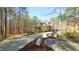 Scenic view of a stone and siding home with a long driveway, surrounded by mature trees and natural landscaping at 5640 Bella Terra Ct, Wake Forest, NC 27587