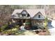 Aerial view of a stone and siding home featuring a covered front porch, well-maintained landscaping, and a wooded lot at 5640 Bella Terra Ct, Wake Forest, NC 27587