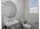 Bright half bath featuring a pedestal sink, oval mirror, and toilet by a window at 6351 Perry Creek Rd, Raleigh, NC 27616