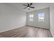 Simple bedroom with hardwood flooring, ceiling fan, and large windows offering natural light at 6351 Perry Creek Rd, Raleigh, NC 27616
