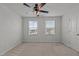 A bright bedroom with neutral carpet, a ceiling fan, and two windows with neighborhood views at 6351 Perry Creek Rd, Raleigh, NC 27616