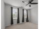 Large bedroom with ceiling fan and three windows dressed in gray curtains for ample light at 6351 Perry Creek Rd, Raleigh, NC 27616
