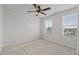Bright bedroom with neutral carpet, ceiling fan, and two windows providing natural light and neighborhood views at 6351 Perry Creek Rd, Raleigh, NC 27616