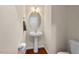 Cozy half-bathroom with a pedestal sink, oval mirror, and wood flooring, perfect for guests at 7 Starwood Ln, Durham, NC 27712
