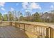 A wooden back deck features railings and overlooks a large backyard with trees and playground at 1019 Thompson Rd, Four Oaks, NC 27524