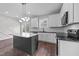 Open kitchen with dark island, stainless appliances, modern light fixtures, and slider door to deck at 1019 Thompson Rd, Four Oaks, NC 27524