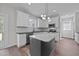 Modern kitchen with white cabinets, stainless appliances, dark island, and modern light fixture at 1019 Thompson Rd, Four Oaks, NC 27524