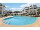 Large outdoor pool with lounge chairs and seating areas, surrounded by well-maintained townhomes under a sunny, cloudy sky at 10320 Sablewood Dr # 107, Raleigh, NC 27617