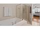 Bright bathroom showcasing a tiled shower, soaking tub, and a glimpse into the connected bedroom at 10511 Rosegate Ct # 203, Raleigh, NC 27617