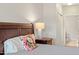 Bedroom showing a plush bed with floral pillows, a nightstand with lamp, and a glimpse into the en-suite bathroom at 10511 Rosegate Ct # 203, Raleigh, NC 27617