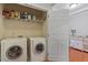 Well-organized laundry room featuring a side-by-side washer and dryer, storage shelves, and a utility sink at 10511 Rosegate Ct # 203, Raleigh, NC 27617