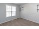 Bedroom with a large window, neutral carpet, and wallpaper accent wall with floating shelves at 203 Patterdale Pl, Benson, NC 27504