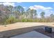 View of a spacious backyard with dormant grass and mature trees, providing privacy at 2306 Stoney Spring Dr, Raleigh, NC 27610