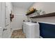 Functional laundry room with washer, dryer, shelving, and wallpaper at 308 Masden Rd, Holly Springs, NC 27540