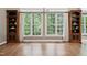 Living room featuring hardwood floors, custom bookshelves, and large windows providing ample natural light at 3421 Griffice Mill Rd, Raleigh, NC 27610