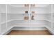 Walk-in pantry with white shelves and hardwood floors providing ample storage space at 409 Tintern Ln, Apex, NC 27523