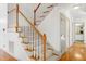 Carpeted staircase features wooden banister, white risers, and leads to hardwood flooring with a view into the bathroom at 509 Edgemore Ave, Cary, NC 27519