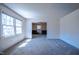 Bright, carpeted living room with a large window and an open doorway to the dining area at 510 Corrida Ave, Durham, NC 27704