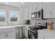 Bright kitchen with white cabinets, marble backsplash, stainless appliances, farmhouse sink, and view from window at 518 W Chisholm St, Sanford, NC 27330