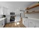 Bright kitchen featuring white cabinets, marble backsplash, stainless steel appliances, and open wood shelving at 518 W Chisholm St, Sanford, NC 27330