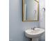 Powder room with pedestal sink, decorative mirror, and light blue walls at 6434 Astor Elgin St, Raleigh, NC 27616