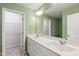 Bathroom with a double vanity, large mirror, green walls, and an adjacent walk-in closet at 6434 Astor Elgin St, Raleigh, NC 27616