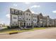 Beautiful three-story townhomes featuring varied neutral colors and well-maintained lawns on a sunny day at 6434 Astor Elgin St, Raleigh, NC 27616