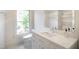 Bright bathroom featuring white marble countertop vanity and a window overlooking a lush, green outdoor space at 7216 Bluffside Ct, Raleigh, NC 27615