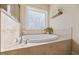 Bright bathroom featuring a soaking tub with tile surround and a frosted glass block window at 8008 Upper Lake Dr, Raleigh, NC 27615