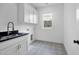 Clean laundry room with white cabinets, black countertop, patterned flooring, and a window at 8201 Southmoor Hill Trl, Wake Forest, NC 27587