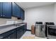 Well-appointed laundry room featuring navy blue cabinets, stainless steel washer/dryer, and ample counter space at 909 Lake Boone Trl, Raleigh, NC 27607