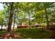 Backyard featuring a lush lawn, mature trees, and a charming deck with stairs at 102 Caymus Ct, Cary, NC 27519