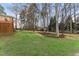 Wide shot of the backyard with a lush green lawn, mature trees, and mulched plant beds at 102 Caymus Ct, Cary, NC 27519