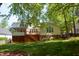 Backyard featuring a lush lawn, mature trees, and a charming deck with stairs at 102 Caymus Ct, Cary, NC 27519