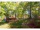 A view of the back of the house from the yard, with a wooden porch and green grass, surrounded by trees at 102 Caymus Ct, Cary, NC 27519