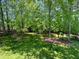 A well-maintained backyard features mature trees, manicured lawns, and a partial fence for privacy at 102 Caymus Ct, Cary, NC 27519
