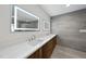 Modern bathroom featuring double sinks, lighted mirrors, and gray tile accent wall at 10509 Leslie Dr, Raleigh, NC 27615