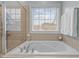 Relaxing bathtub with window, shower glass and neutral tile surround at 1203 Fairview Club Dr, Wake Forest, NC 27587