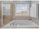 Relaxing bathtub with tiled surround, shower, and a bright window at 1203 Fairview Club Dr, Wake Forest, NC 27587