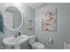 Cozy powder room with pedestal sink, round mirror, and charming floral wall art at 1203 Fairview Club Dr, Wake Forest, NC 27587