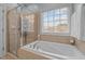 Relaxing bathtub with tiled surround, shower, and a bright window at 1203 Fairview Club Dr, Wake Forest, NC 27587