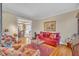 Inviting living room with hardwood floors, red sofa, floral armchair, and view into dining room at 12504 Ribbongrass Ct, Raleigh, NC 27614