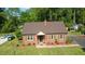 Charming brick home featuring a well-manicured lawn, mature trees, and a cozy front porch at 132 Lord Ashley Rd, Raleigh, NC 27610