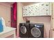 Functional laundry area with black washer and dryer, white cabinets, and pink accent wall at 132 Lord Ashley Rd, Raleigh, NC 27610