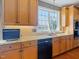Kitchen featuring black dishwasher, granite countertop, stainless steel sink, and natural wood cabinets at 132 Mantle Dr, Clayton, NC 27527