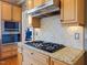 Close up of kitchen detailing cooktop, range hood, granite countertops, and stone tile backsplash at 132 Mantle Dr, Clayton, NC 27527