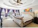 Main bedroom suite with a large bed, tray ceiling, bay window, and ample natural light creates a relaxing and luxurious space at 132 Mantle Dr, Clayton, NC 27527