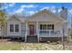 Charming single-story home featuring a covered front porch, red door, stone pathway, and cozy cottage style at 1384 Sims Bridge Rd, Kittrell, NC 27544