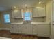 Well-lit kitchen featuring white cabinets, a tiled backsplash, and stainless steel sink at 1421 Deer Crossing Ct, Henderson, NC 27536